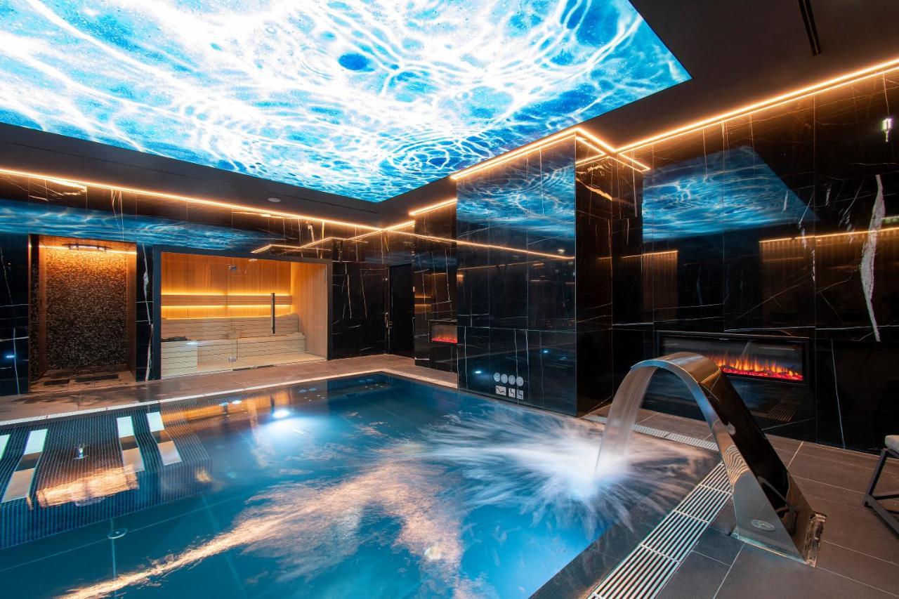 Epic Sana Marques Hotel Lissabon Exterior foto The image shows a luxurious indoor swimming pool area with a sleek, modern design. The pool has clear blue water and features a stylish waterfall spout. Above the pool, there is an imaginative ceiling that displays a vibrant image of water ripples, e