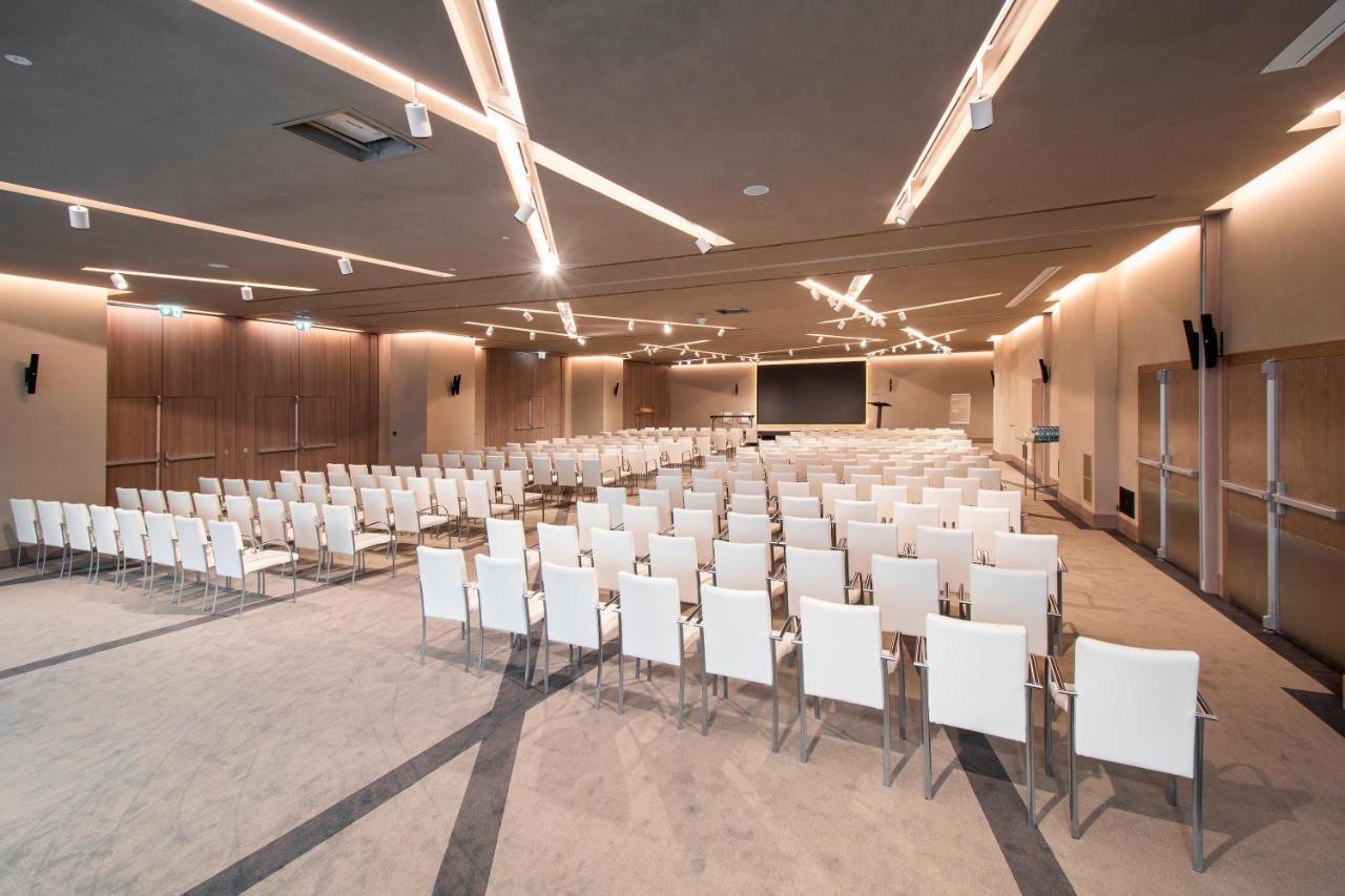 Epic Sana Marques Hotel Lissabon Exterior foto The photo depicts a spacious conference or seminar room set up for an event. It features a large number of white chairs arranged in rows facing a central area where a presentation or speaking event would likely take place. The room is well-lit with m