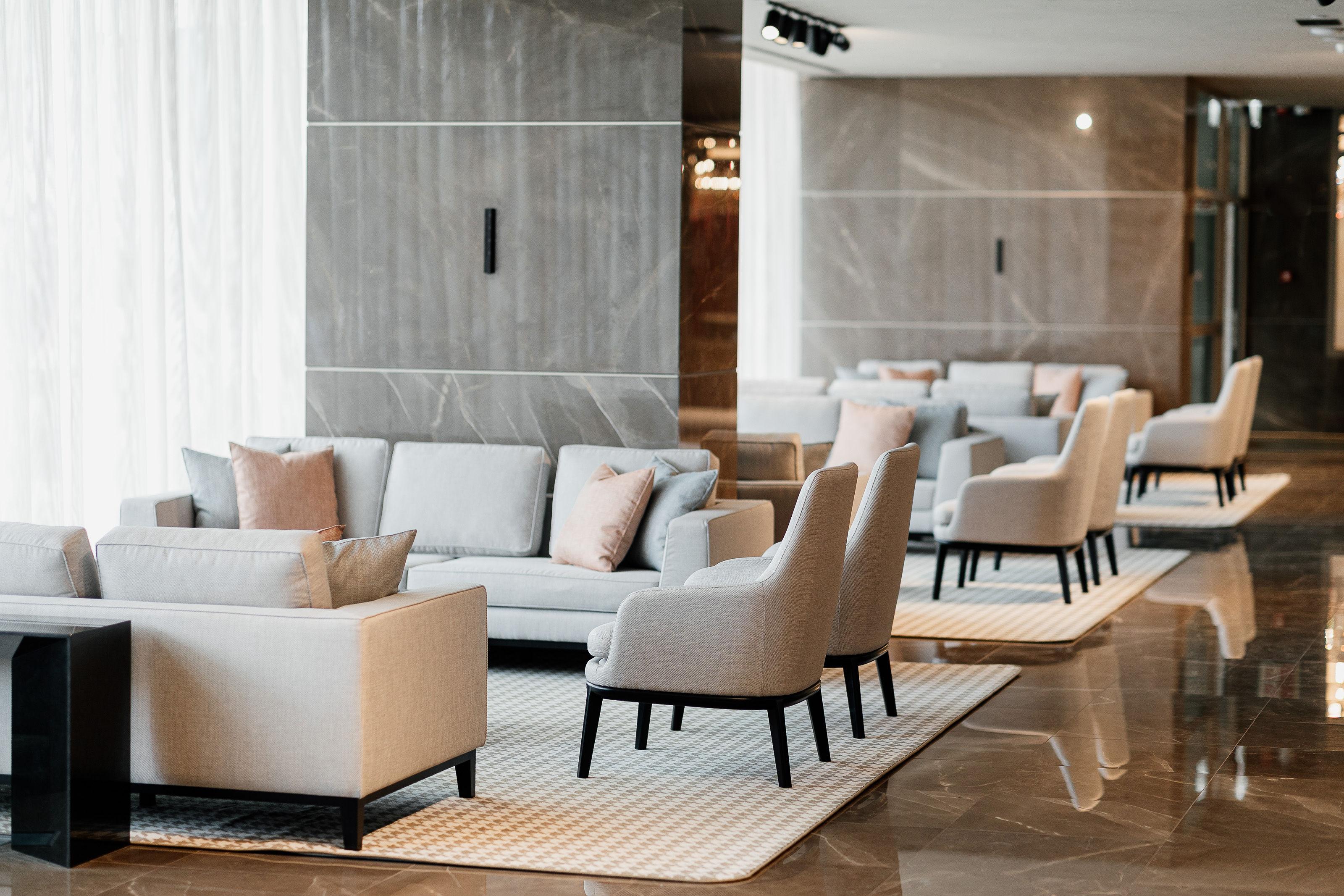 Epic Sana Marques Hotel Lissabon Exterior foto The photo displays a modern and stylish lounge area. It features a series of light gray sofas and armchairs, arranged with soft cushions in pastel shades. The seating is positioned on a light-colored area rug, which contrasts with the polished floor.