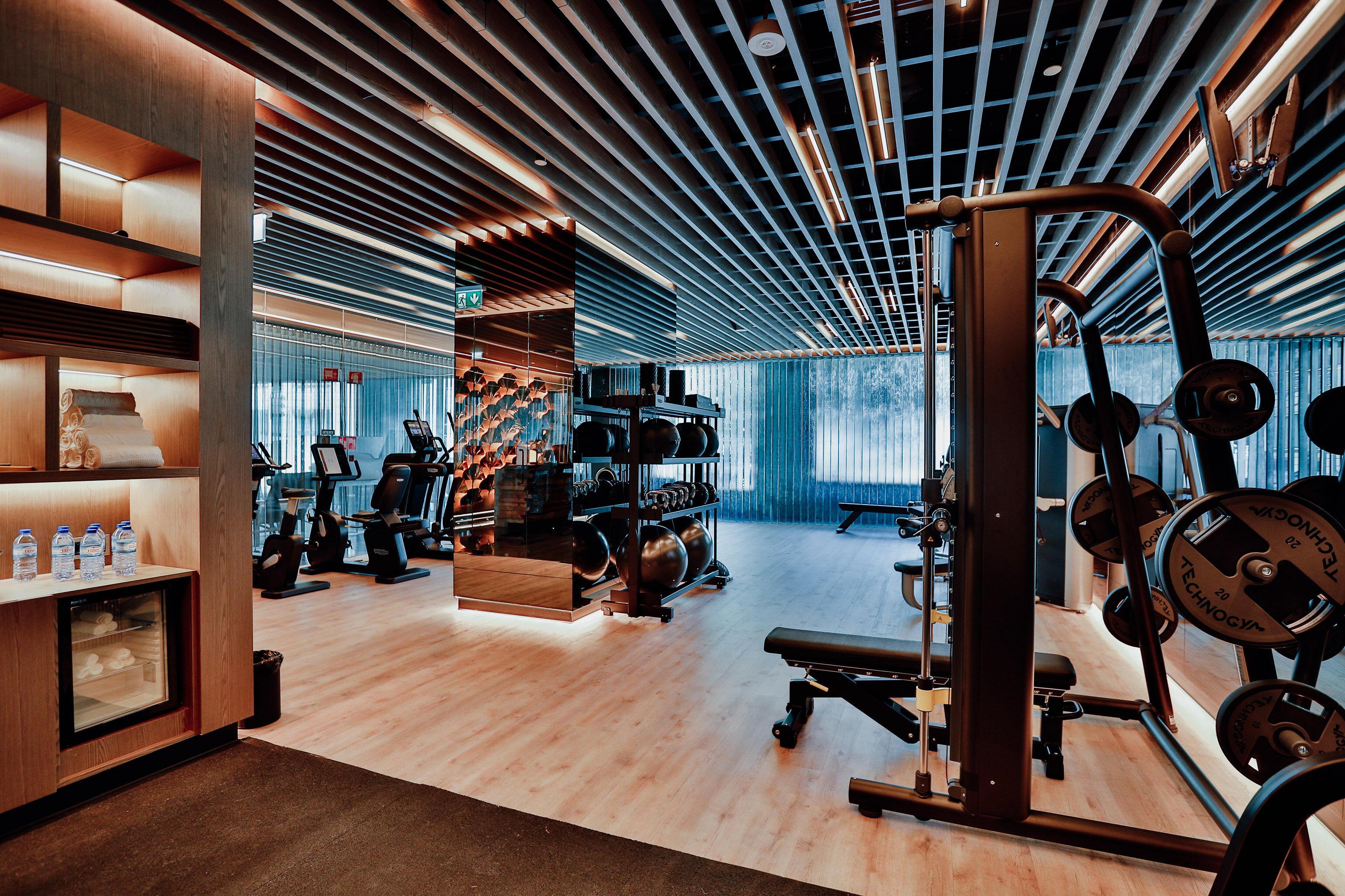 Epic Sana Marques Hotel Lissabon Exterior foto The photo shows a modern gym or fitness center. It features a spacious room with wooden flooring and an illuminated ceiling. There are various exercise machines, including treadmills and weightlifting equipment, arranged neatly throughout the space. 