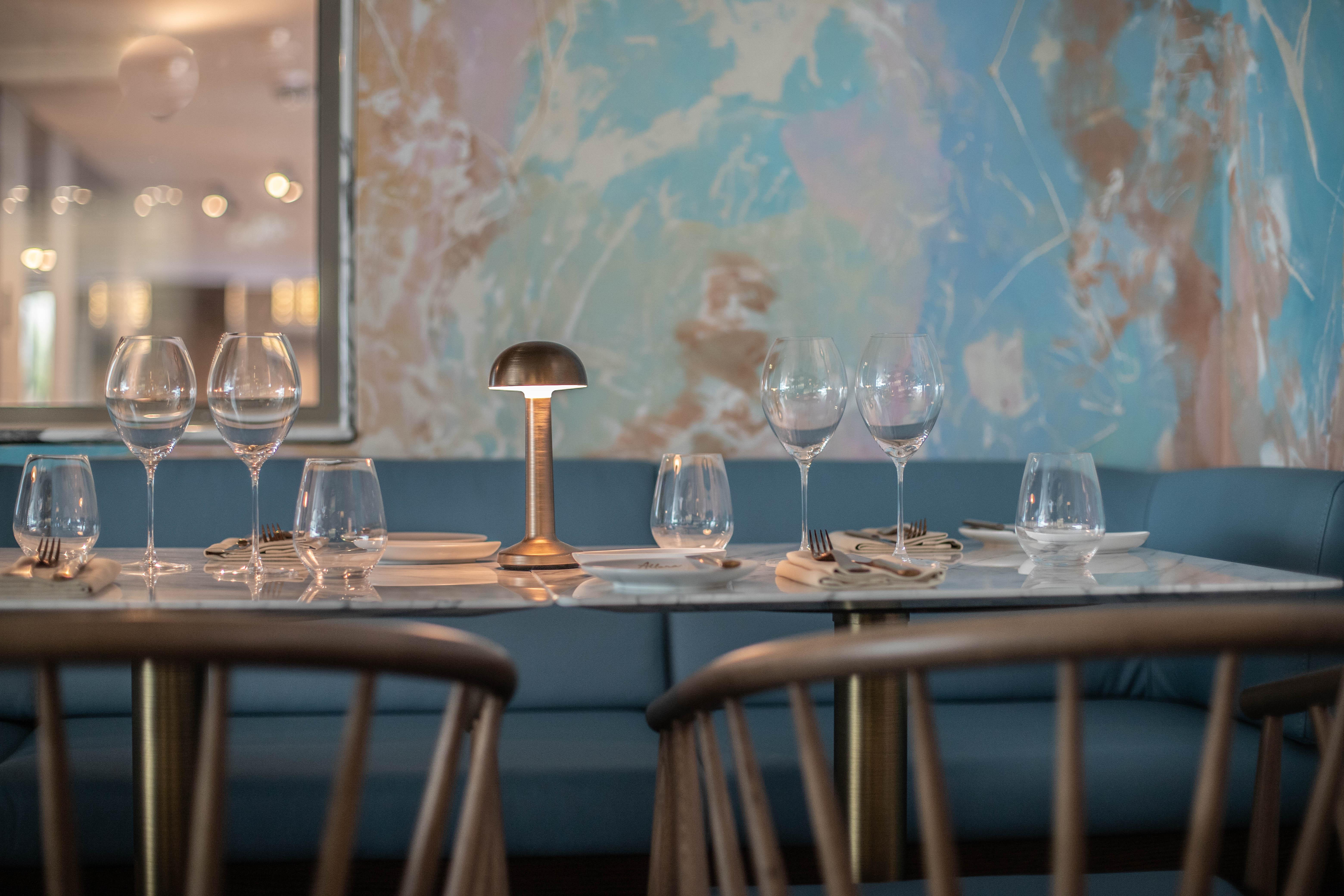 Epic Sana Marques Hotel Lissabon Exterior foto The photo shows a cozy dining table set for a meal. There are several wine glasses and water glasses arranged neatly on the table, along with a small lamp providing ambient lighting. The table has a marble surface and is complemented by a blue uphols