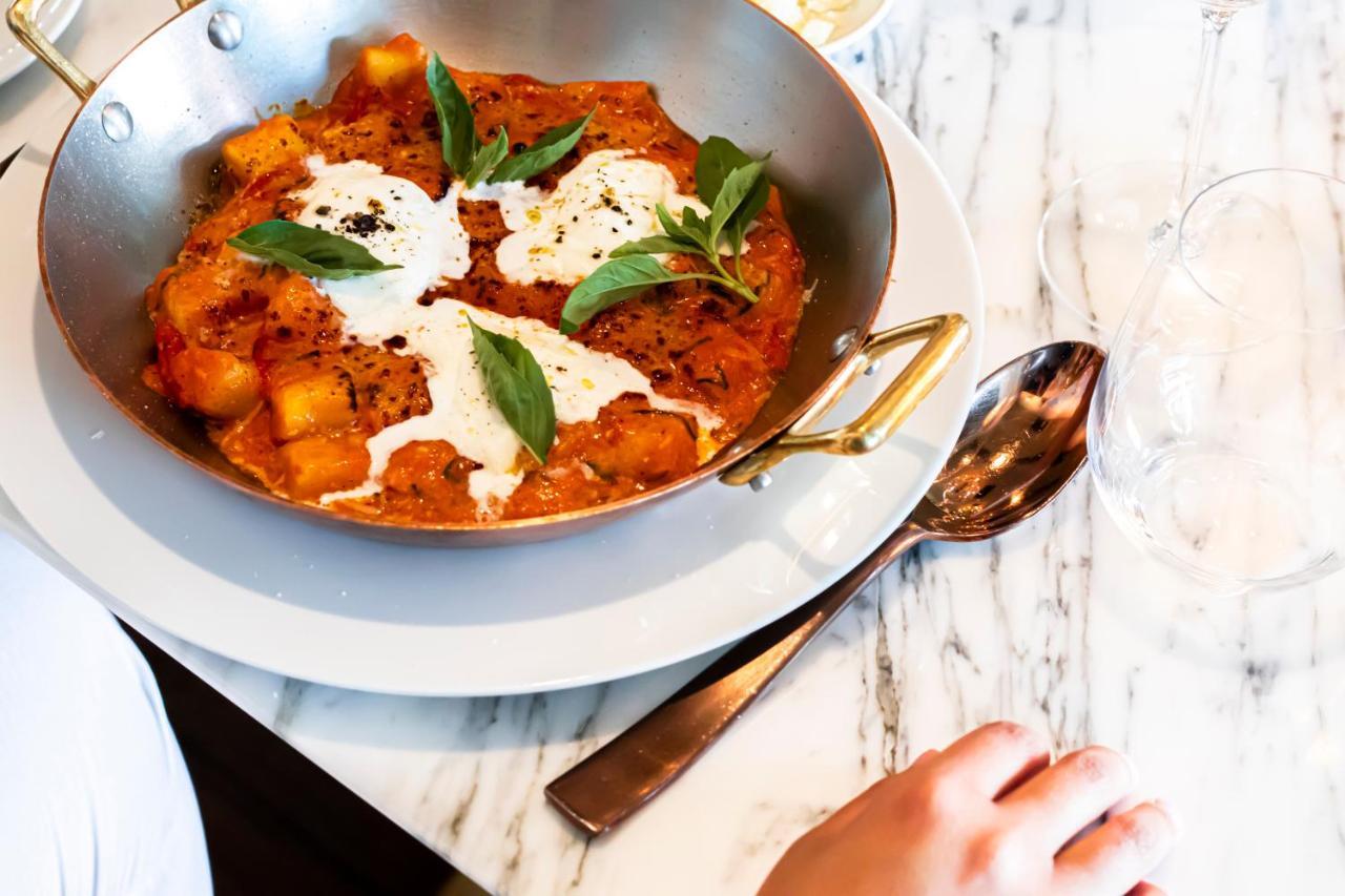 Epic Sana Marques Hotel Lissabon Exterior foto The photo shows a dish of gnocchi served in a creamy tomato sauce. The gnocchi pieces are orange and appear to be mixed with herbs, while there are dollops of a white creamy sauce on top. Fresh basil leaves are scattered on the dish for garnish. The 
